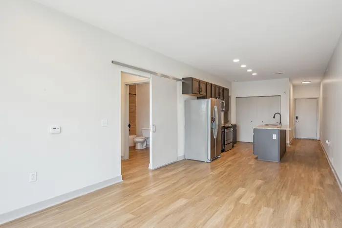 Modern open-concept kitchen featuring sleek stainless steel appliances, elegant wood flooring, and ample natural light.