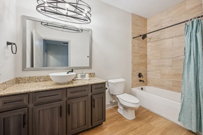 Modern bathroom with elegant granite countertop, vessel sink, and inviting bathtub surrounded by warm-toned tiles for a luxurious spa-like experience.