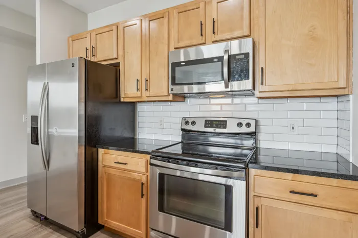 Modern kitchen with sleek stainless steel appliances, warm wooden cabinets, and a stylish subway tile backsplash.