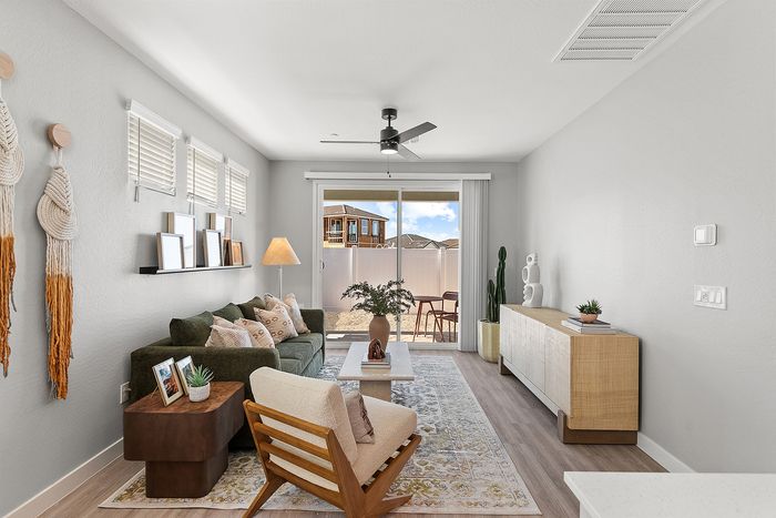 Chic and cozy living room with modern decor, a stylish green sofa, elegant wooden furniture, and large glass doors opening to a bright outdoor space.