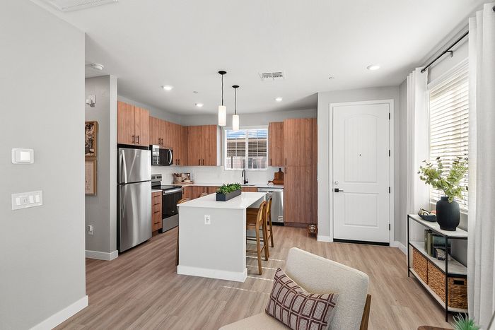 Contemporary apartment kitchen with sleek stainless steel appliances, warm wood cabinets, and a cozy island with seating, perfect for modern living.