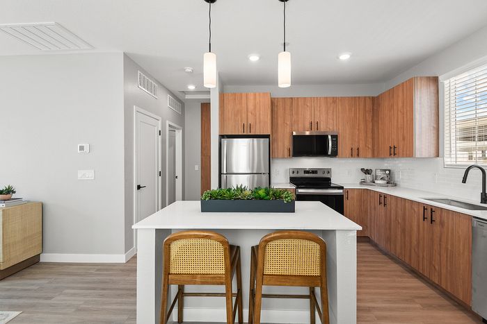 Chic modern kitchen with sleek wooden cabinetry, stainless steel appliances, and an inviting breakfast island with cozy seating.