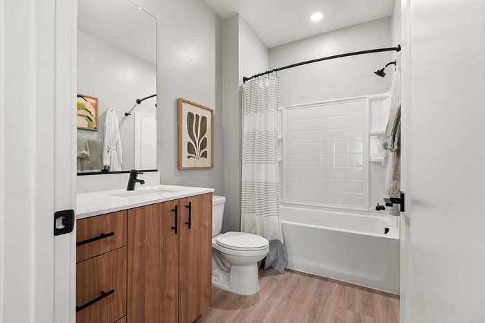 Modern bathroom featuring sleek wooden cabinetry, textured tile shower, and elegant minimalist decor.