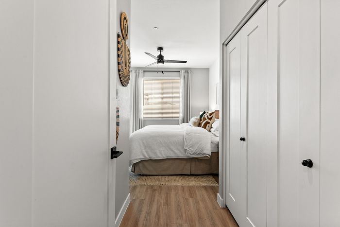 Inviting bedroom with cozy white bedding, modern decor, and natural light filtering through elegant blinds, offering a serene and stylish retreat.