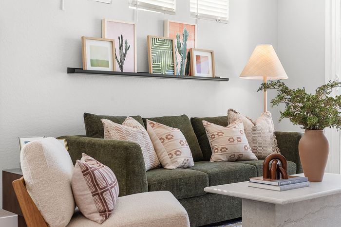 Charming living room with an elegant green sofa, stylish cushions, and modern artwork, enhanced by warm lighting and vibrant decor.