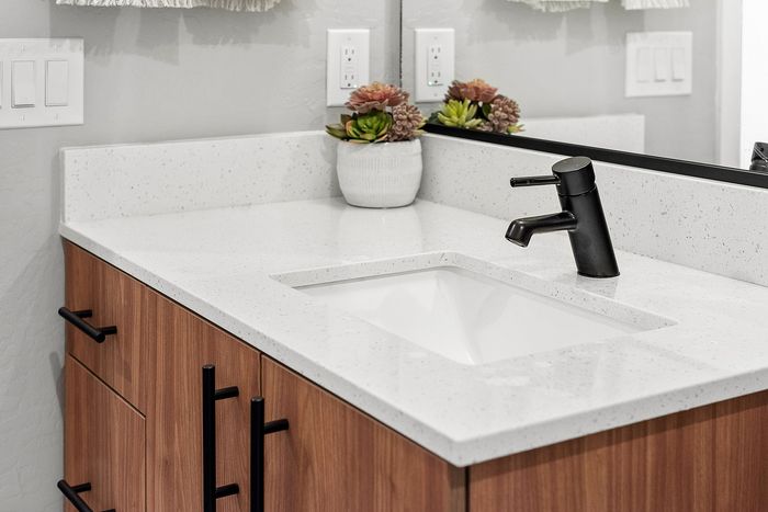 Elegant bathroom countertop with sleek white quartz finish, modern black faucet, and decorative succulent plant.