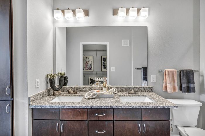 Modern bathroom with elegant double vanity, granite countertops, and sleek fixtures. Enhanced lighting and sophisticated decor add a touch of luxury.