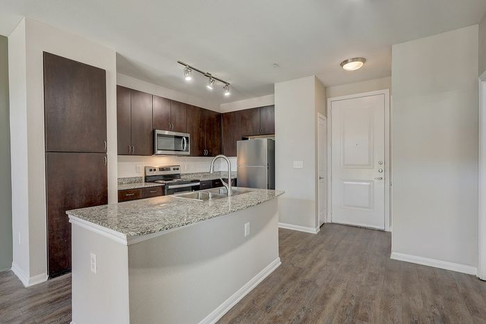 Modern kitchen with sleek granite countertops, dark wood cabinetry, and stainless steel appliances, offering a contemporary and inviting space.