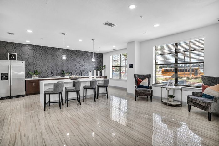 Modern open-concept kitchen and living space with glossy tiled floors, stylish bar seating, and large windows for natural light.