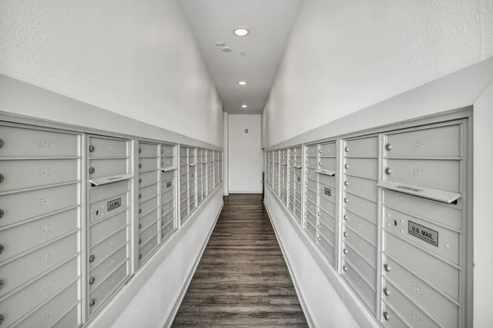 Modern apartment mailroom corridor with sleek, organized mailboxes and elegant wood flooring.