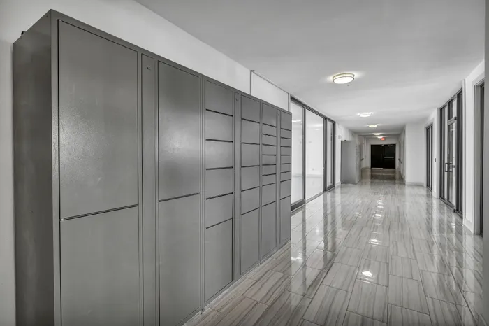 Elegant apartment hallway featuring sleek parcel lockers and glossy tiled floors, illuminated by modern lighting.