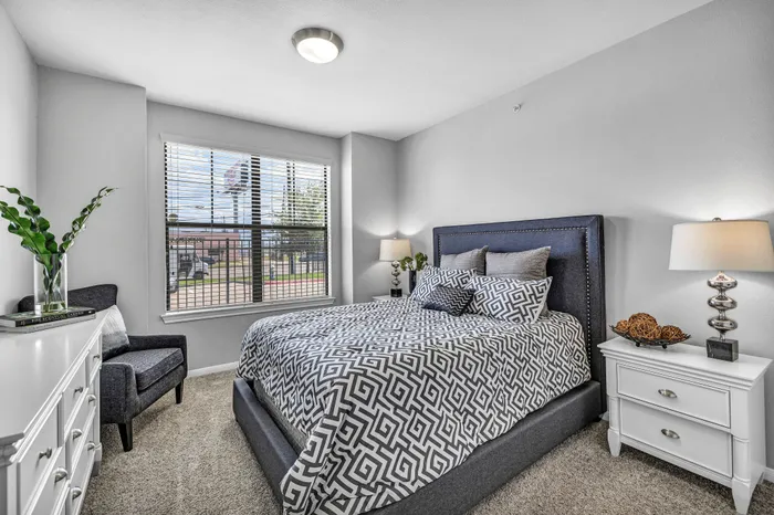 Elegant bedroom with modern decor, featuring a plush bed, stylish bedside lamps, and a large window offering abundant natural light.