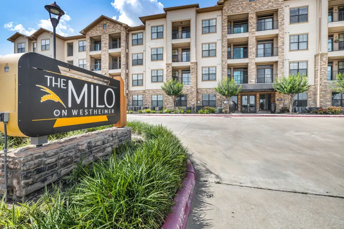 Elegant four-story apartment complex with modern stone accents and lush landscaping at The Milo on Westheimer.