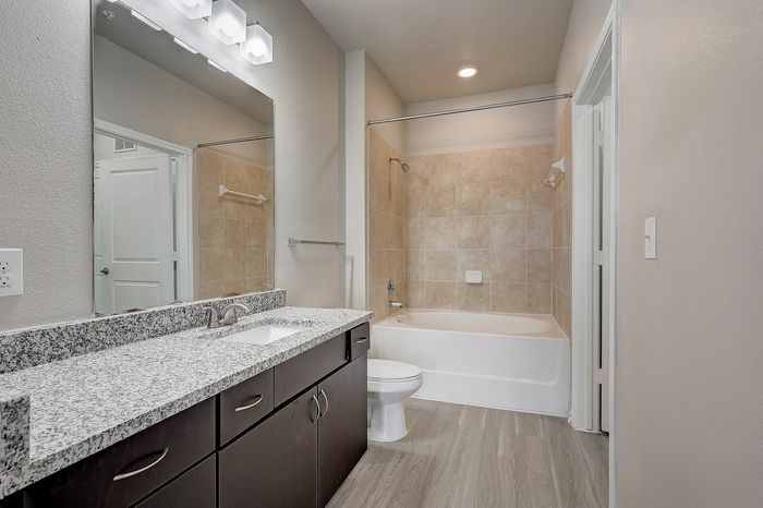 Elegant bathroom with granite countertop, modern fixtures, and a tiled bathtub shower combo.