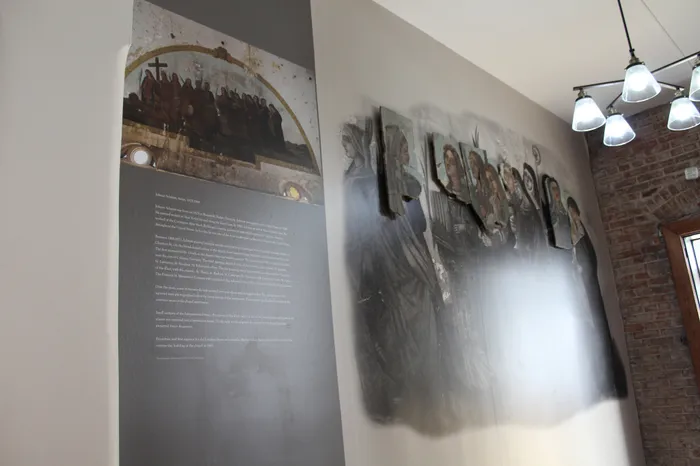 Charming interior wall with vintage artwork and stylish lighting, blending historical and modern elements in a cozy setting.