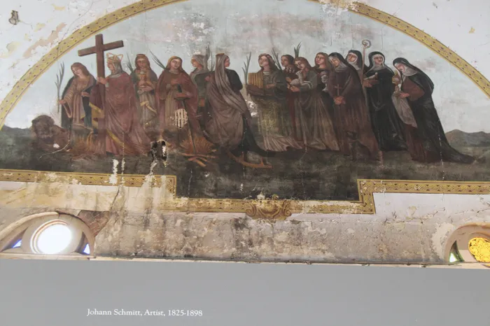 Intricately detailed religious mural featuring historical figures in vibrant robes, with a cross and a lion, set in a beautifully aged archway.
