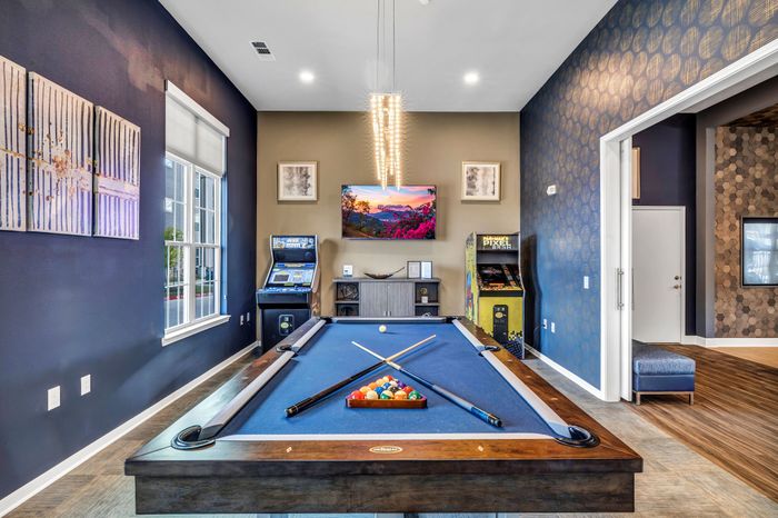Chic game room featuring a stylish pool table, arcade machines, and modern decor with vibrant artwork.