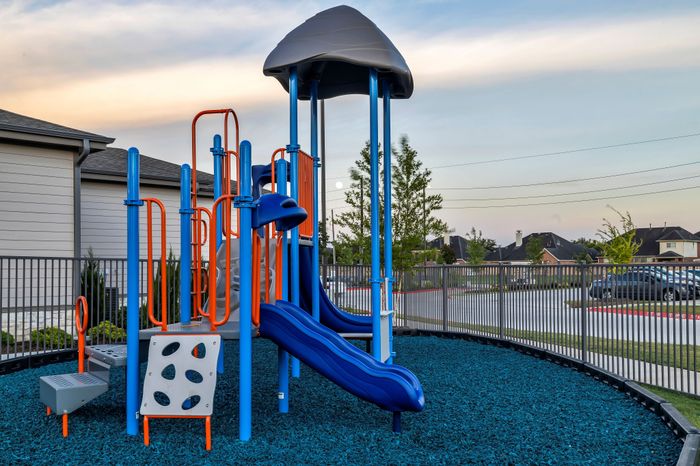 Inviting playground with vibrant blue and orange equipment set against a serene residential backdrop, perfect for family-friendly living.