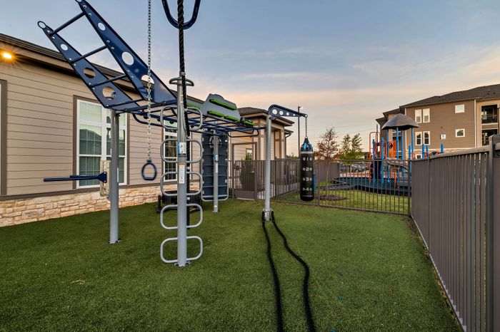 Modern playground and outdoor workout area featuring climbing equipment and a punching bag, ideal for active lifestyle in a family-friendly community.