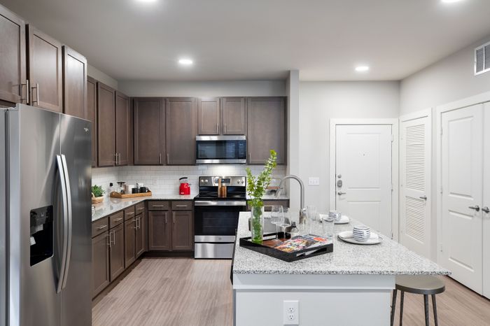 Modern kitchen with sleek stainless steel appliances, granite countertops, and elegant wooden cabinetry in a stylish apartment.