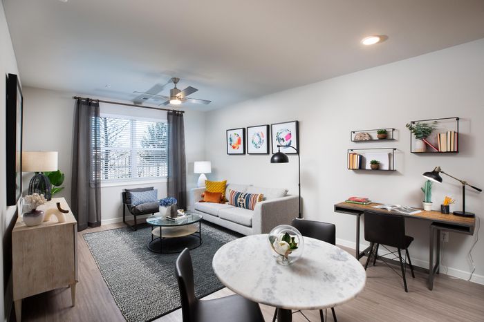 Bright and modern living room with stylish decor, featuring a cozy sofa, chic artwork, and an elegant desk space.