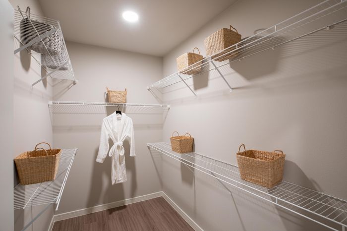 Spacious walk-in closet with elegant wire shelving, wicker baskets, and a luxurious white robe, offering ample storage and organization.