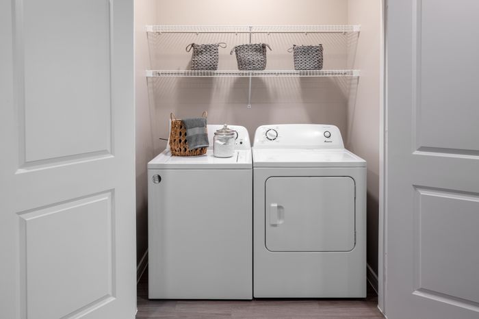 Modern laundry room with sleek washer, dryer, and stylish storage baskets on open shelving.