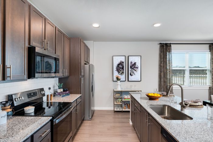 Modern kitchen with sleek dark wood cabinets, stainless steel appliances, and a spacious granite island countertop. Bright and airy ambiance with natural light from large windows.