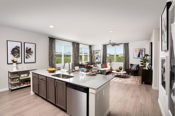 Modern open-concept living room with large windows, stylish kitchen island, and elegant decor, offering a bright and inviting atmosphere.