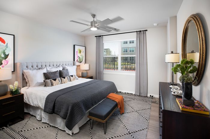 Elegant bedroom featuring a plush king-sized bed, stylish decor, and large window with ample natural light.