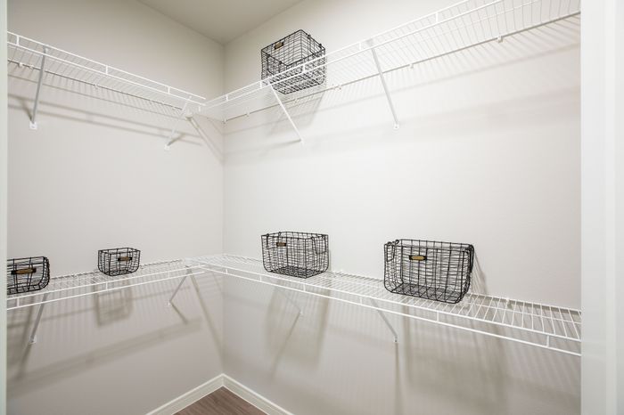 Spacious walk-in closet with sleek white wire shelving and stylish black storage baskets, perfect for organized living.