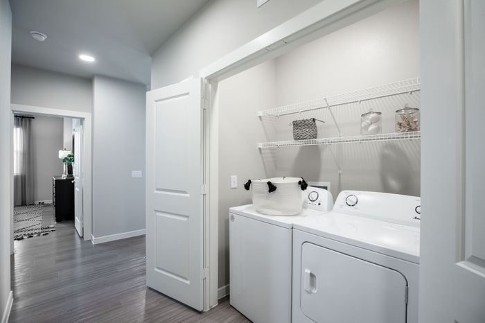 Sleek modern laundry room with washer, dryer, and ample shelving for storage in a stylish apartment.