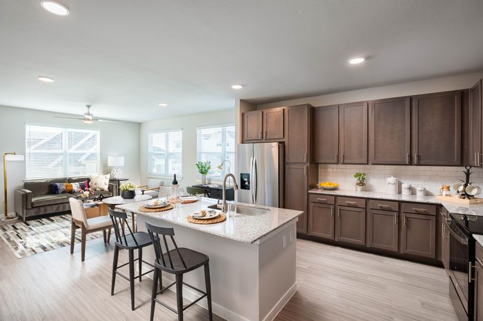 Bright and modern open-concept kitchen and living area with sleek cabinets, stylish island, and cozy seating; perfect for entertaining.
