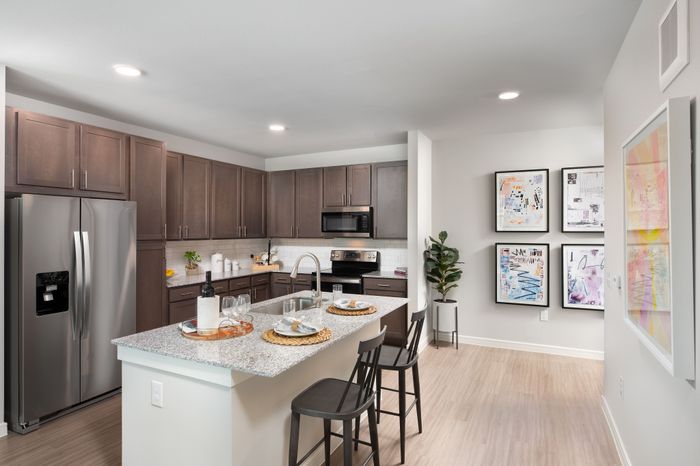 Modern kitchen with sleek granite countertops, stainless steel appliances, and stylish dark wood cabinetry, featuring a cozy breakfast bar for casual dining.