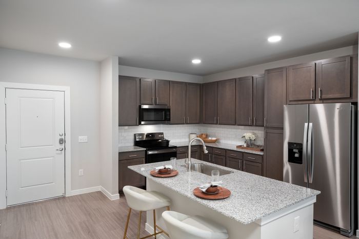 Modern kitchen with sleek dark wood cabinets, stainless steel appliances, and a sophisticated granite island with seating.