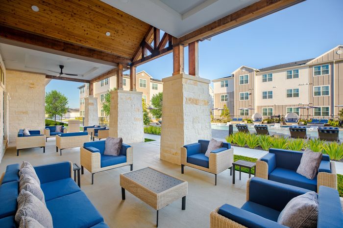 Inviting outdoor lounge area with comfortable blue seating and a scenic view of the luxurious apartment complex and pool.