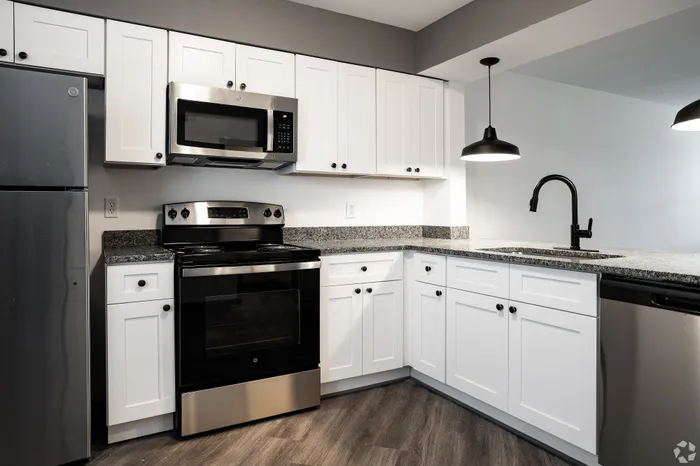 Modern kitchen with sleek stainless steel appliances, elegant granite countertops, and stylish pendant lighting, offering a perfect blend of function and aesthetics.