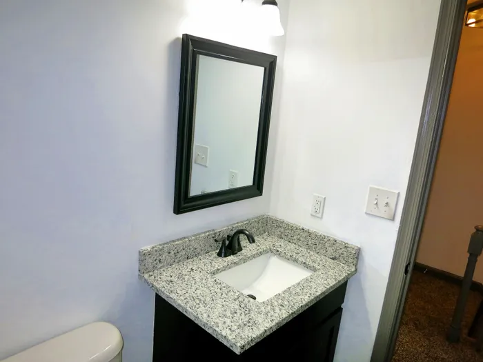 Modern bathroom with elegant granite countertop and sleek, framed mirror creating a sophisticated ambiance.