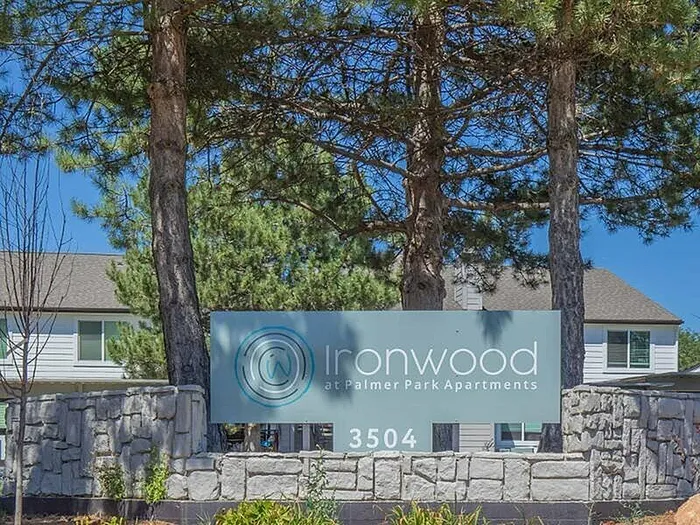Inviting entrance of Ironwood at Palmer Park Apartments surrounded by lush greenery and modern architecture.