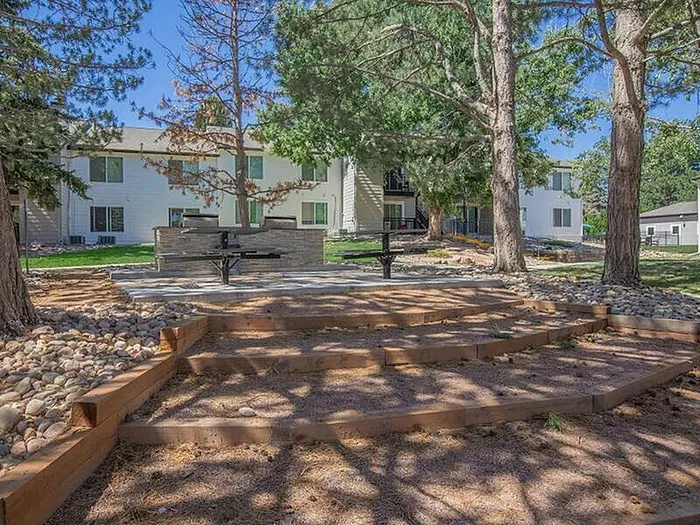 Charming apartment complex with lush greenery, inviting outdoor patio, and serene natural surroundings.