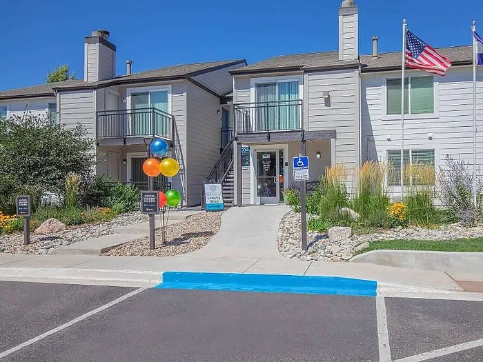 Inviting apartment complex entrance with manicured landscaping, vibrant balloons, and convenient accessibility features.