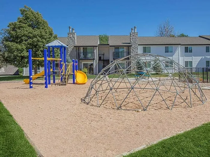 Inviting apartment community with a fun playground featuring slides and a climbing dome, perfect for families seeking outdoor enjoyment.