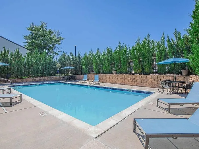 Inviting outdoor pool area with lounge chairs and umbrellas, surrounded by lush greenery and a tranquil setting.