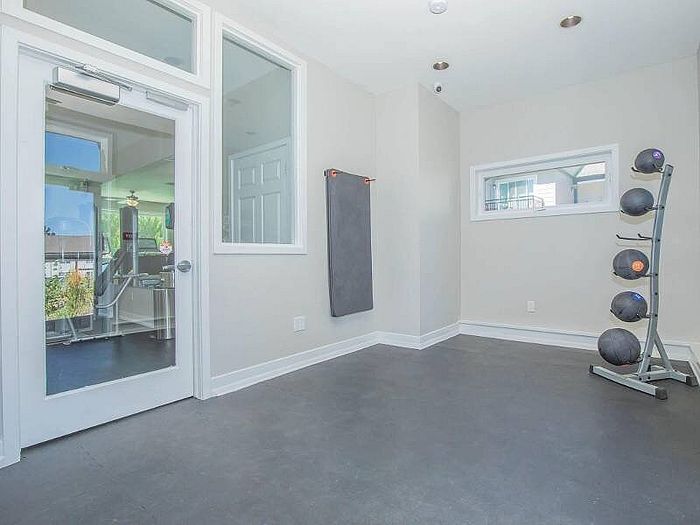 Bright and airy exercise room with modern equipment and large windows offering natural light.