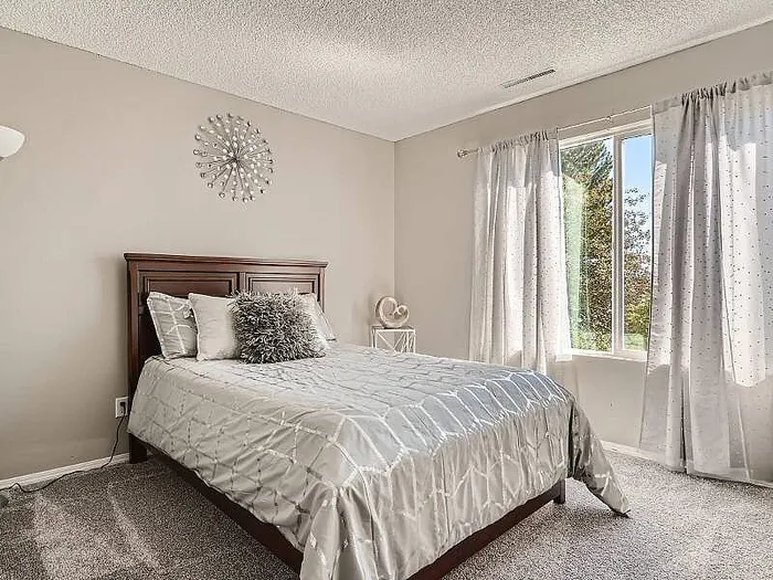 Inviting bedroom with elegant decor, plush bedding, and a sunlit window offering a serene view.