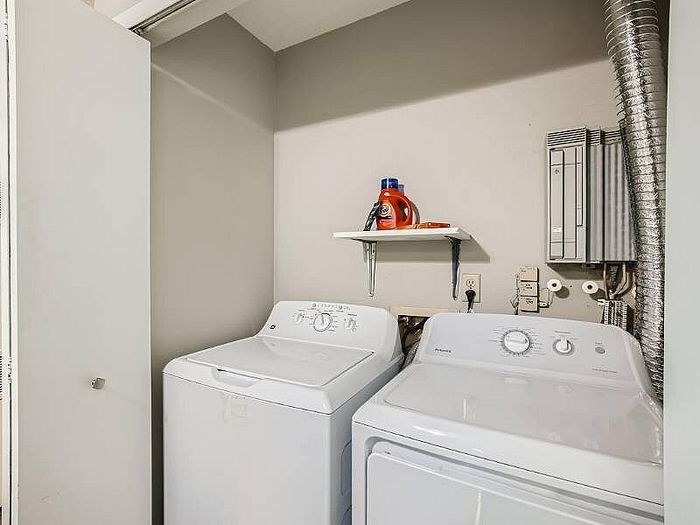Chic laundry area featuring a modern washer and dryer set beneath a convenient shelf stocked with essentials.