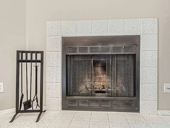 Cozy fireplace with elegant tile surround and classic metal fire tools, ideal for a warm and inviting living space.