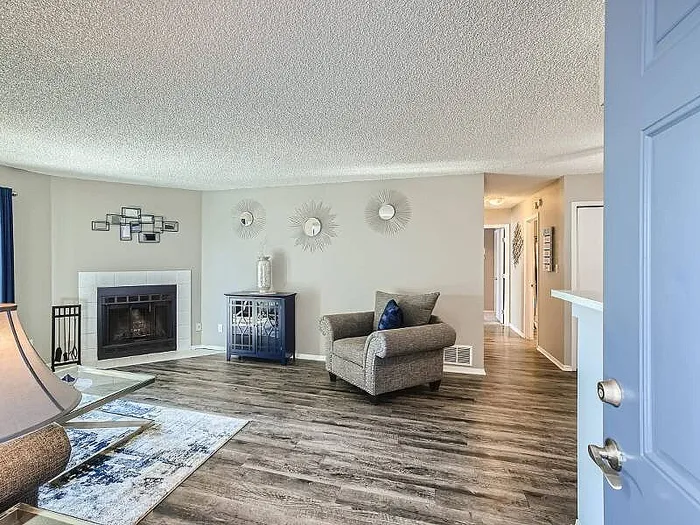 Inviting living room featuring elegant modern decor, a cozy fireplace, and stylish wood flooring.