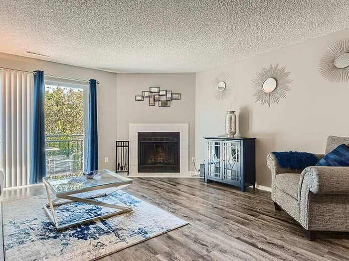 Chic living room with modern decor, featuring a cozy fireplace, elegant furniture, and vibrant blue accents, complemented by natural light from large windows.