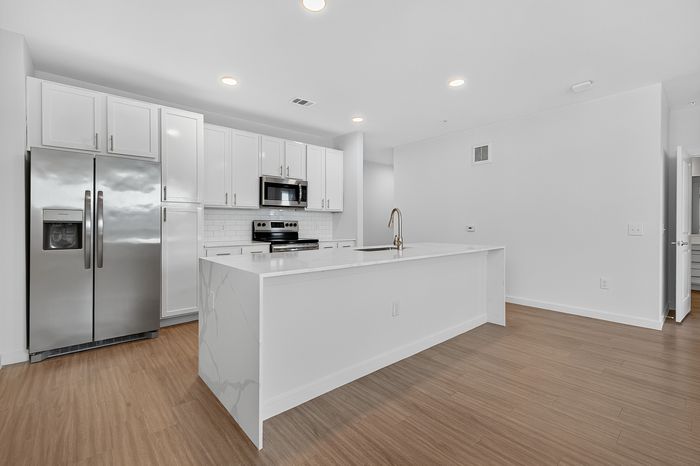 Modern kitchen with sleek stainless steel appliances, bright white cabinetry, and elegant marble countertop on a spacious island.